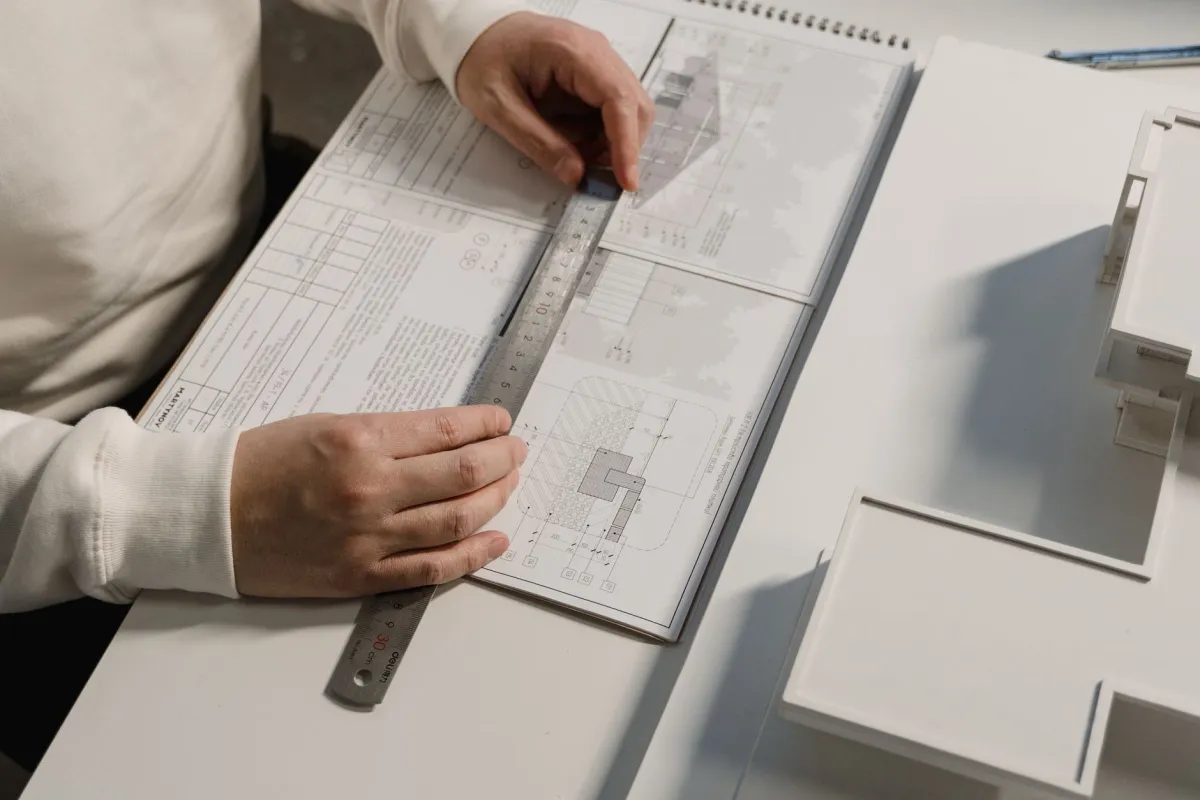 Hands of a person drafting architectural designs with a ruler on paper