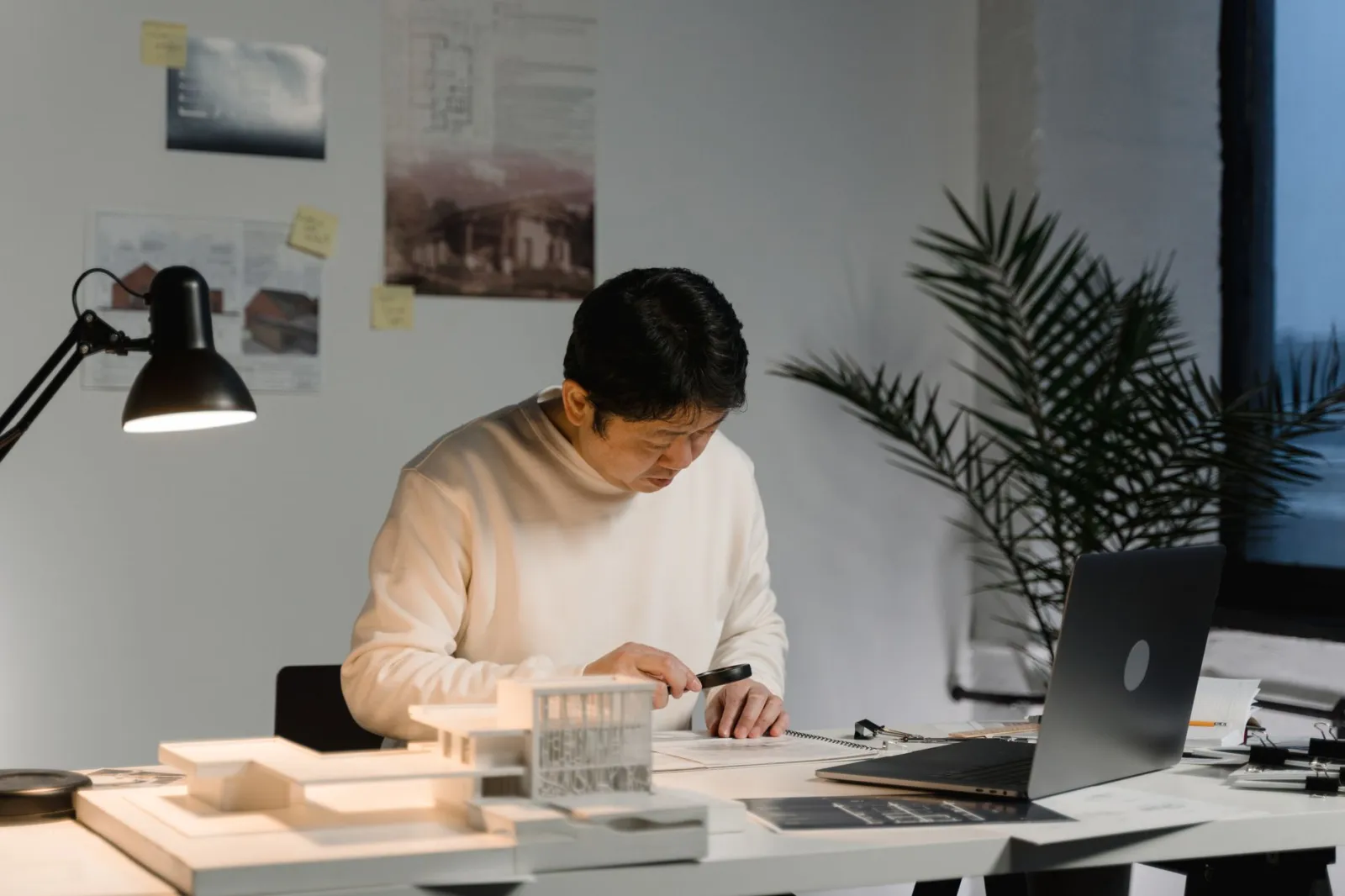 Architect reviewing building models and designs at a desk in a modern office