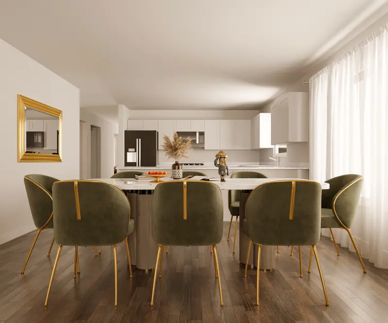 Open-plan dining area with green velvet chairs, a long table and a white kitchen beyond